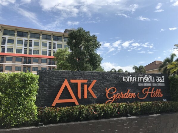 A sign for ATK Garden Hills with a modern building in the background. - ATK Garden Hills (Hat Yai)