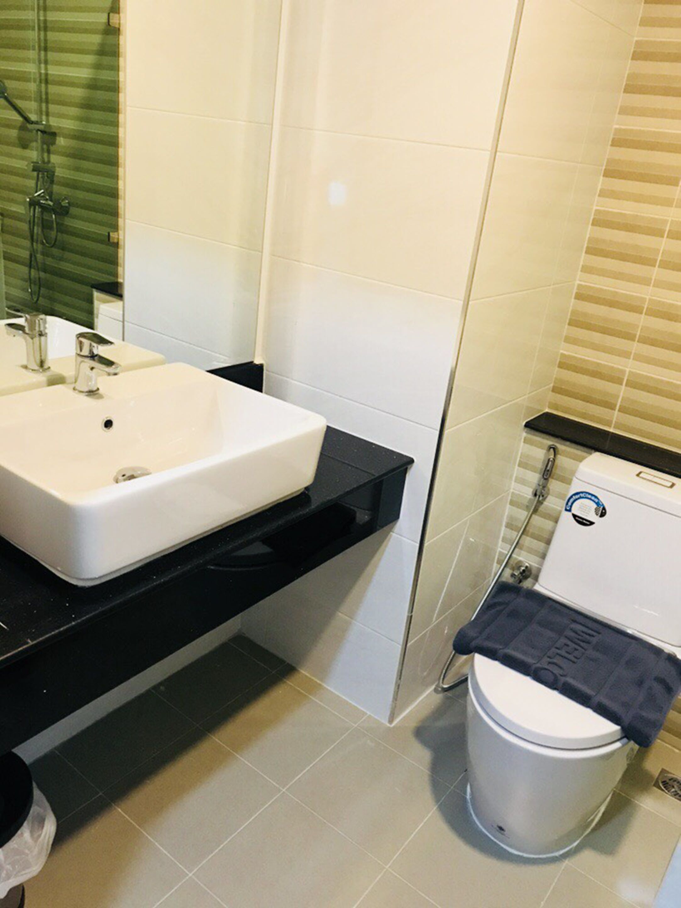 A bathroom with a white sink, black countertop, and a toilet with a blue sticker.