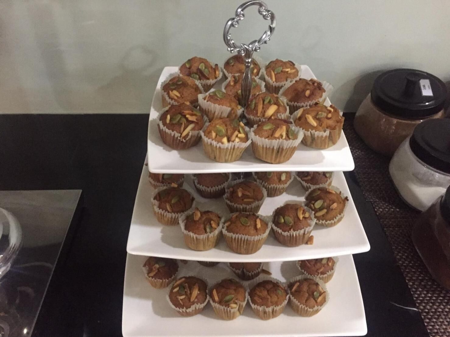 Un présentoir à trois niveaux rempli de muffins, surmonté d’un porte-clés décoratif.