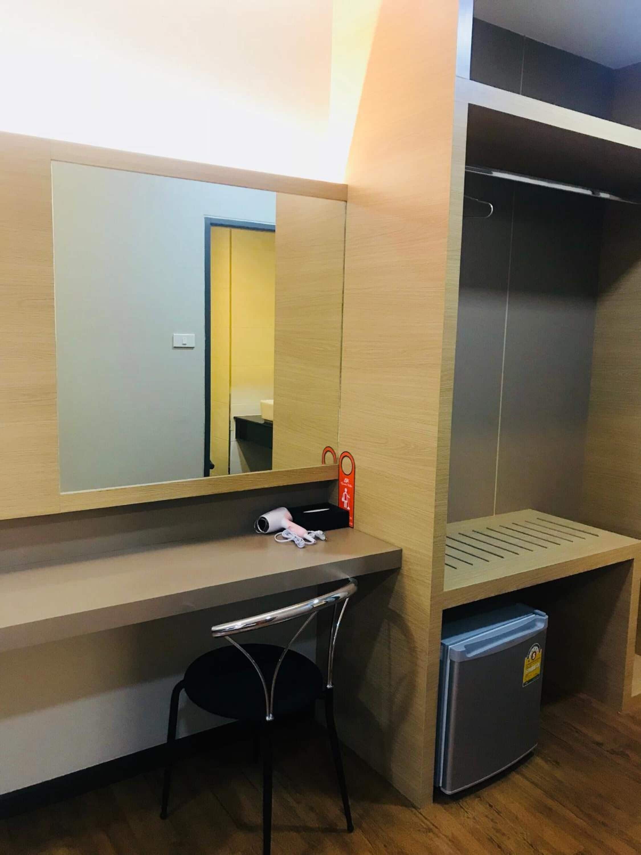 Ein kleines Zimmer mit Schreibtisch, Stuhl und kleinem Kühlschrank.