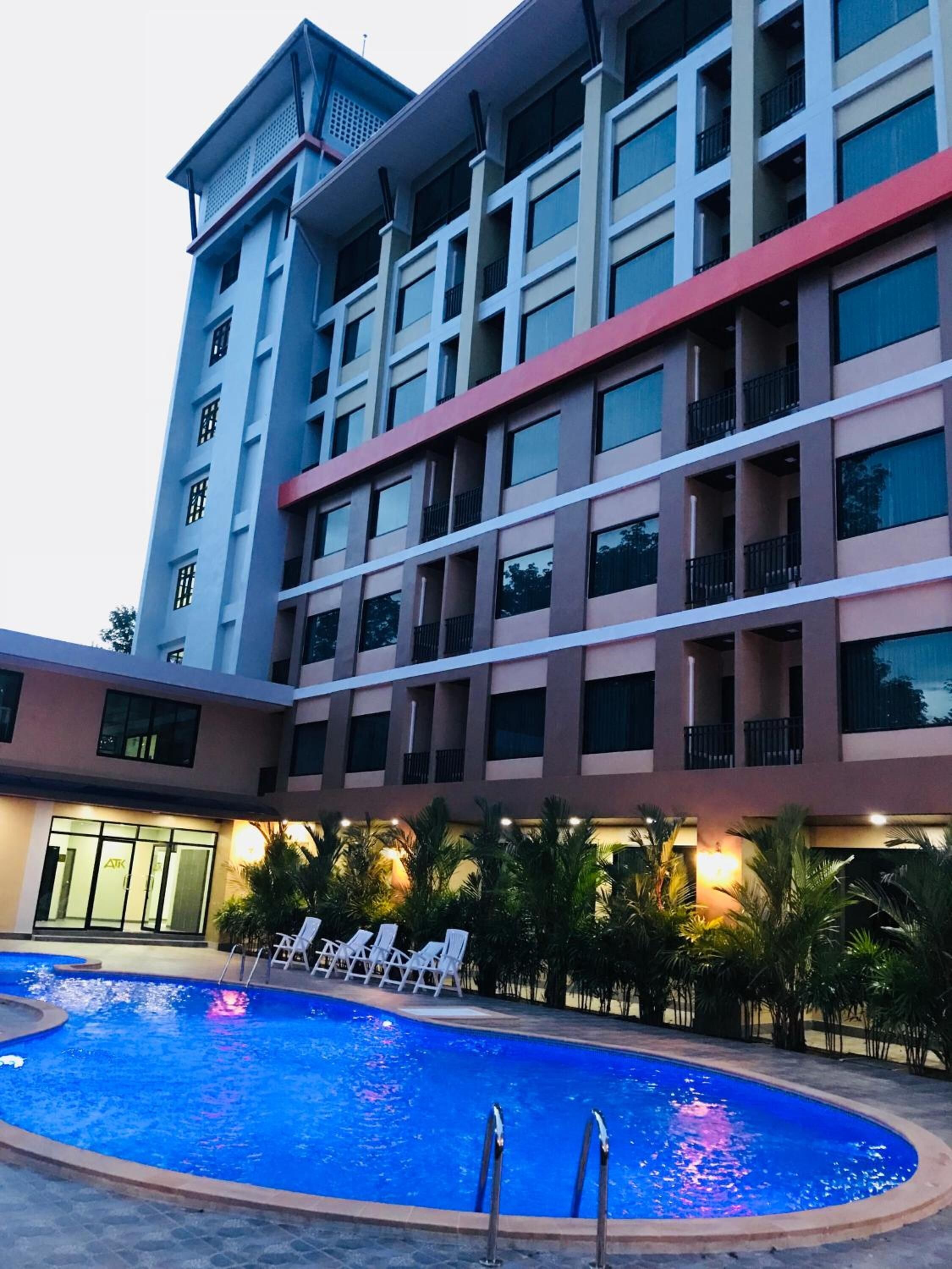 Un hôtel doté d’une piscine, de plusieurs balcons et d’une entrée bien éclairée.