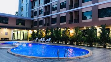 Una piscina al aire libre, sillones reclinables de piscina