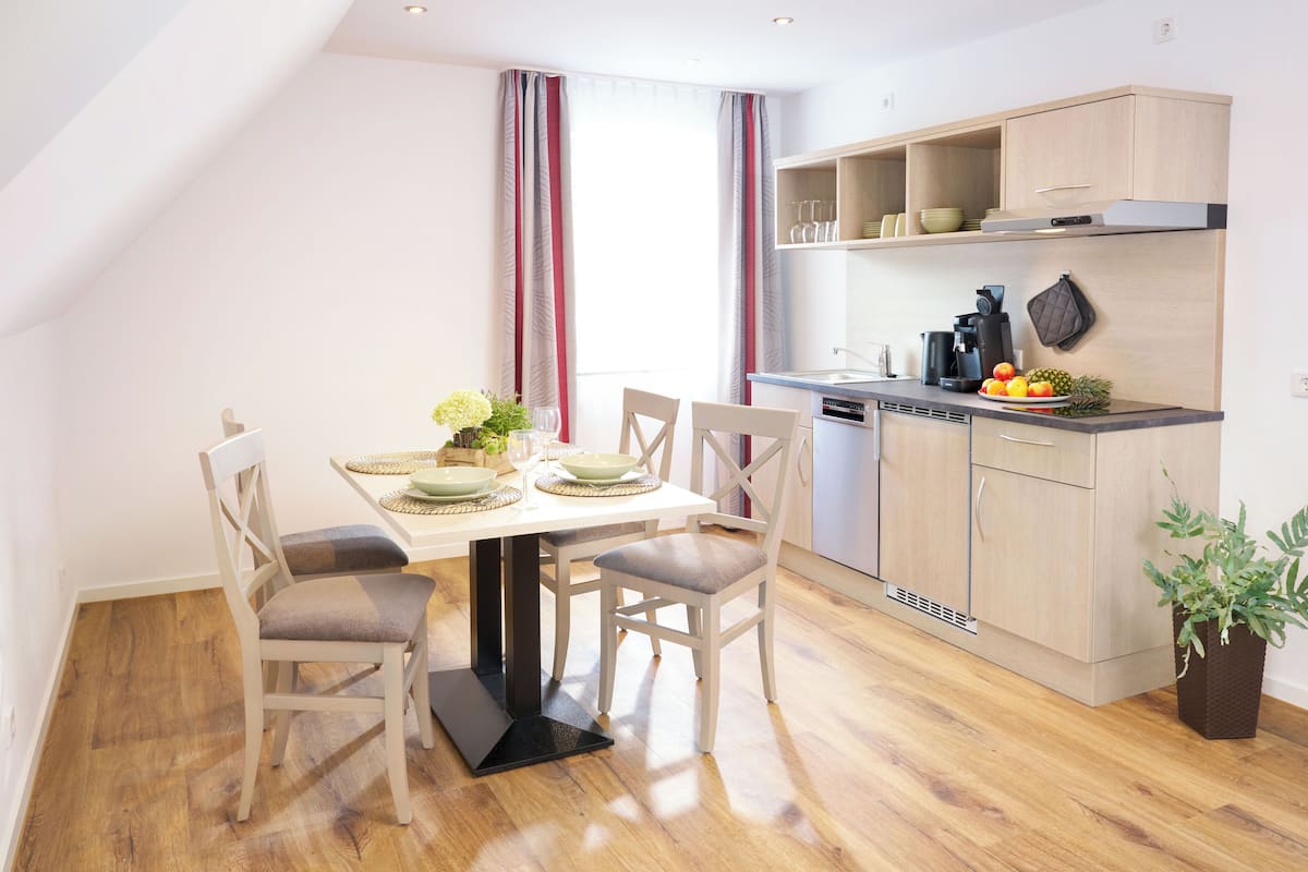 A modern kitchen with wooden cabinets, a dining table with chairs, and a small island.