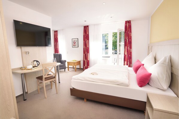 A hotel room with a bed, a desk, a chair, a TV, and a window with curtains. - Hotel Restaurant Haus Dumicketal (Drolshagen)