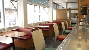 A diner with booths and tables, large windows, and a menu board. - Hotel Siracusa (Escaldes-Engordany)