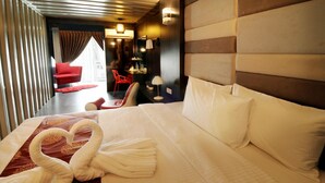 Habitación de hotel con una cama grande, una silla roja, un escritorio y vistas a la ciudad.