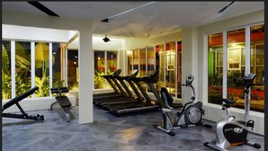 Un gimnasio con cintas de correr, elípticas y una bicicleta estática.