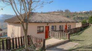 A small building with a thatched roof, a wooden fence, and a paved entrance. - Qabuleka bnb (Nongoma)