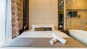 A hotel room with a large bed, a bathroom with a bathtub, and a TV on the wall. - Dorsett Residences Bukit Bintang - Sweet Home KL (Kuala Lumpur)