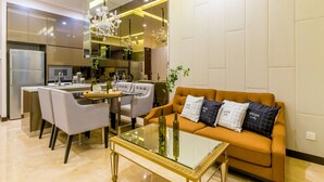 A modern kitchen with stainless steel appliances, a dining area with a glass table, and a living room with a sofa and decorative pillows. - Dorsett Residences Bukit Bintang - Sweet Home KL (Kuala Lumpur)