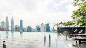 An infinity pool with a city skyline in the background, including the Petronas Towers. - Dorsett Residences Bukit Bintang - Sweet Home KL (Kuala Lumpur)