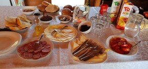 A table set with various food items and utensils, including bread, cheese, tomatoes, and a bottle of olive oil. - Apartments Seherzada (Medulin)