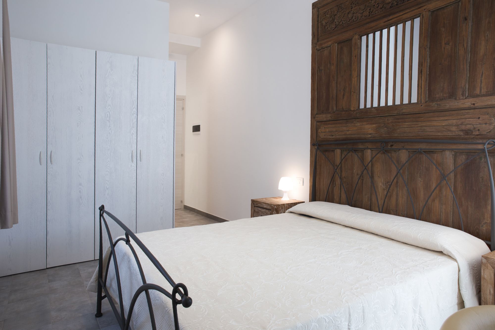 Ein Schlafzimmer mit einem Bett, einem Kleiderschrank und einem Nachttisch mit einer Lampe.