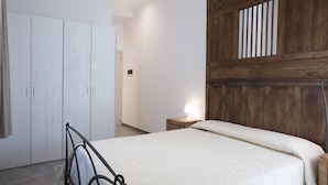 Um quarto com uma cama, um guarda-roupa e uma mesa de cabeceira com abajur.