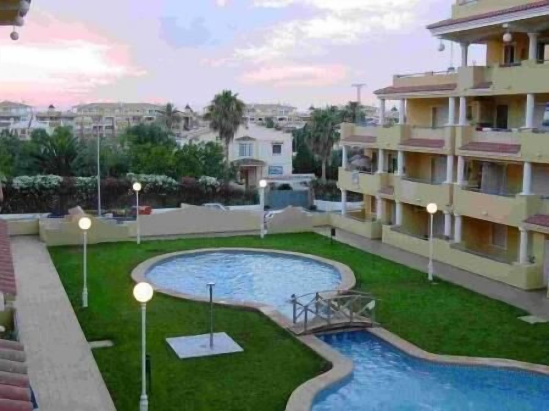 Una zona residenziale con piscina, un piccolo ponte e un prato curato.