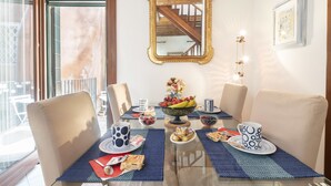 A dining area with a glass table, blue placemats, and a fruit bowl. - Maison Valentina (Venice)