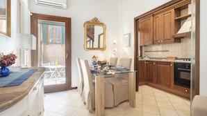 A modern kitchen with wooden cabinets, a glass dining table, and a built-in oven. - Maison Valentina (Venice)