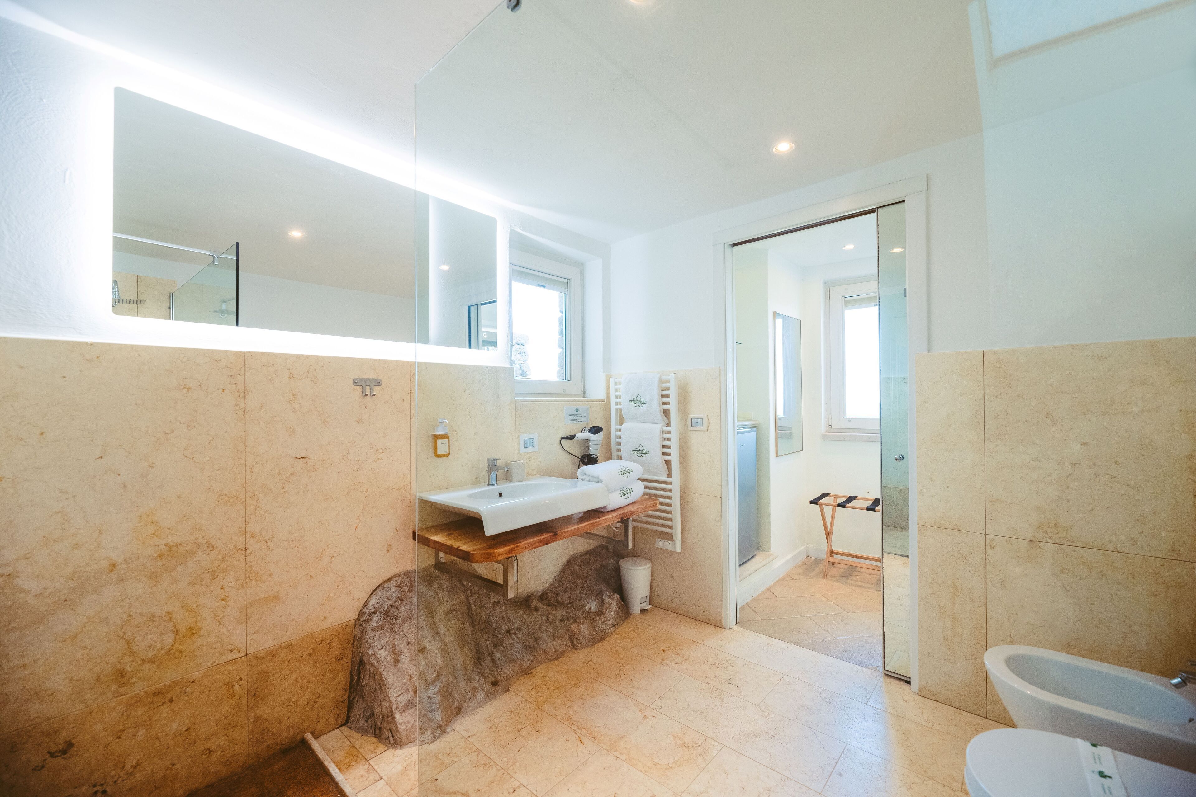 Une salle de bain moderne avec un grand miroir, un meuble-lavabo en bois, une baignoire et des toilettes.