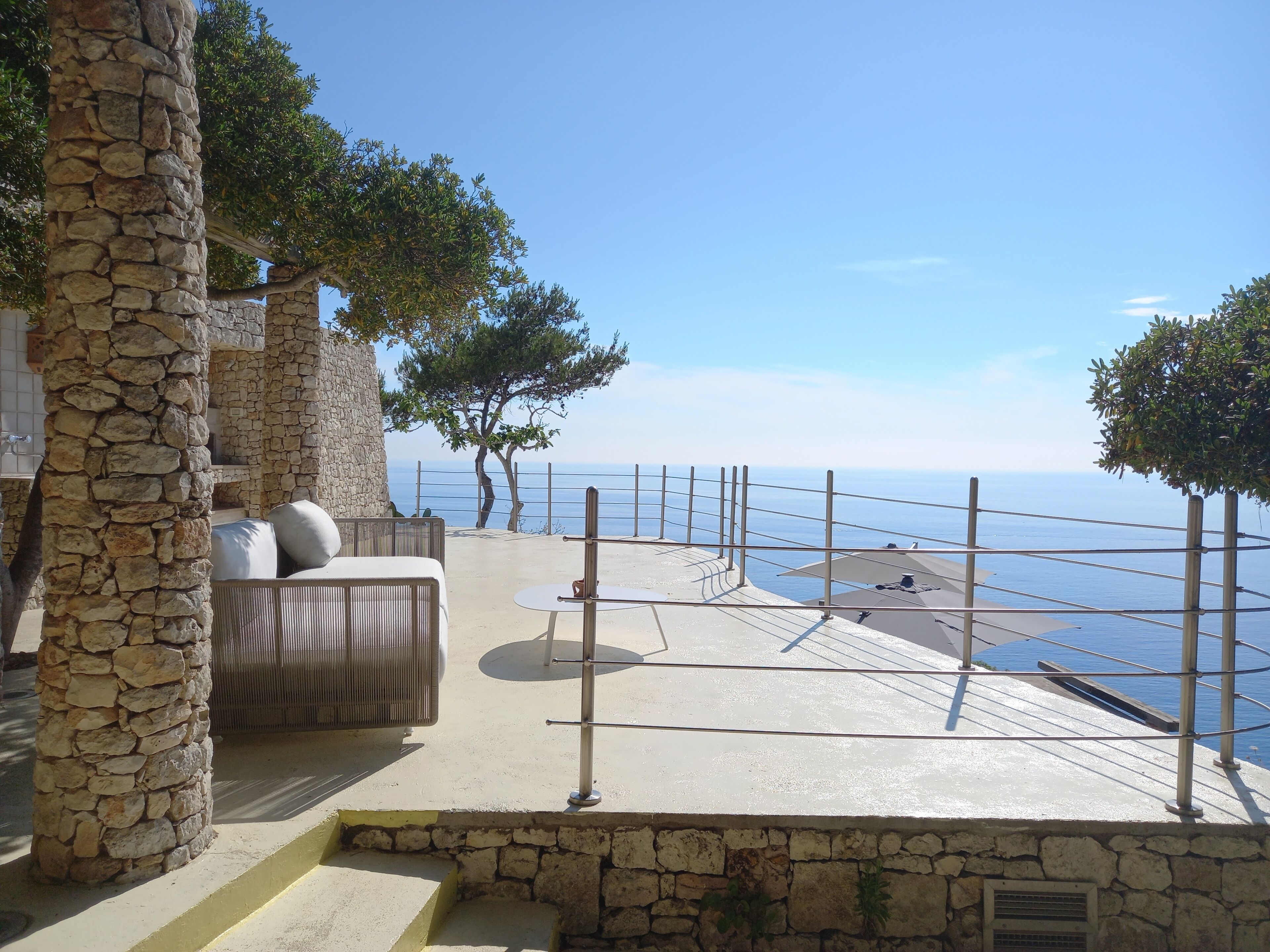 A stone pillar, a seating area with cushions, and a view of the sea.