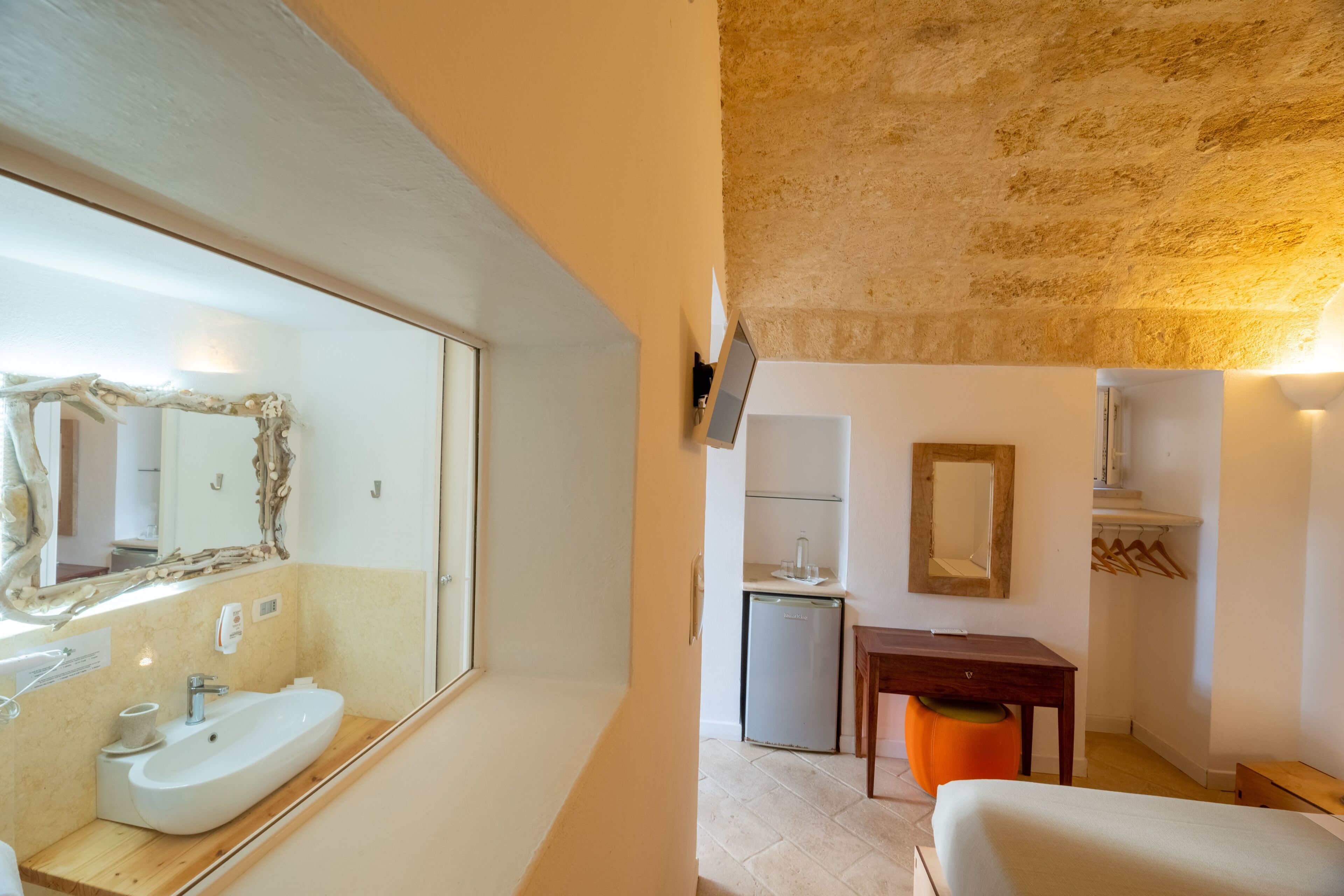 Une salle de bain moderne avec un grand miroir, un lavabo et un petit réfrigérateur.