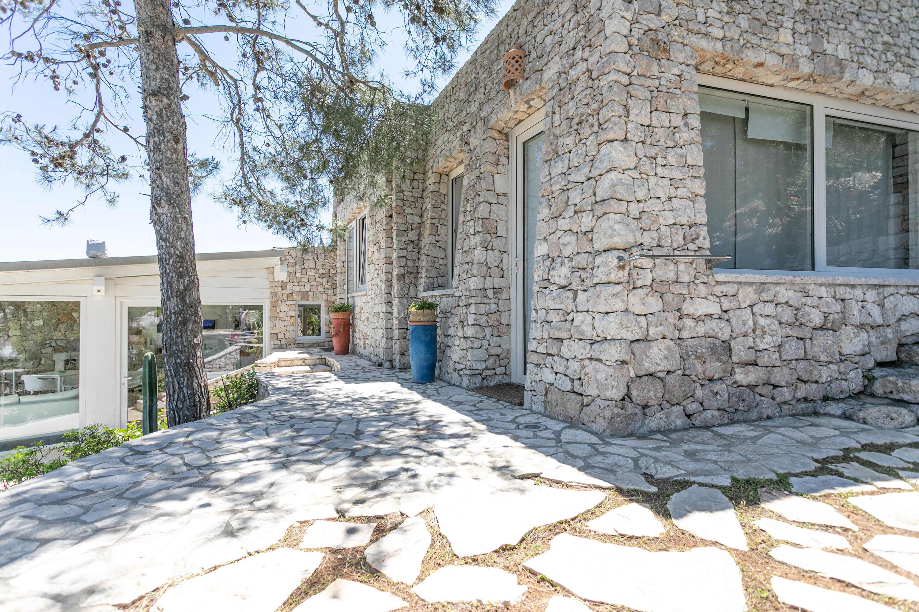 Un bâtiment en pierre doté de grandes fenêtres et d’un chemin en pierre menant à une porte en verre.