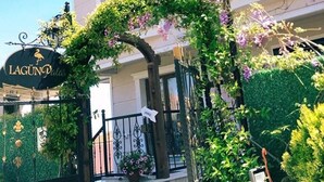 A hotel entrance with a wrought iron gate, a sign reading "LAGUN Palas", and a balcony with purple flowers. - LP Lagun Palas (Altinova)