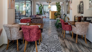 A spacious dining area with a patterned floor, wooden furniture, and a central chandelier. - LP Lagun Palas (Altinova)