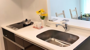 Cozinha moderna com fogão, pia e armários. Há um vaso com flores amarelas no balcão.