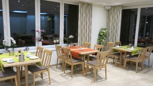 A dining area with tables and chairs, large windows, and a view of the outside. - Landgasthaus Stärk-Berding (Steinfeld)