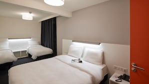 A hotel room with two beds, a red door, a small bedside table with a phone, and a ceiling light fixture. - Le Nex2 (Tarbes)