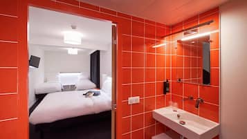 A hotel room with a bed, a white sink, and a mirror.