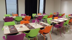 A conference room with multiple tables and colorful chairs, equipped with nameplates and water bottles. - Le Nex2 (Tarbes)