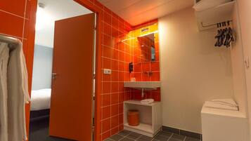 A bathroom with orange tiles, a white sink, a mirror, and a towel rack.