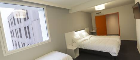 Habitación de hotel con dos camas, una ventana y una puerta.
