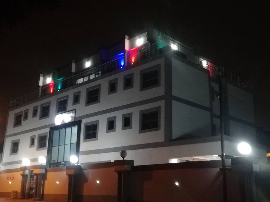 A multi-story building with a prominent entrance and a balcony with colorful lights.