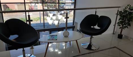 A modern interior with two black chairs, a small table, and a potted plant.