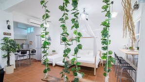A modern bedroom with a canopy bed, a dining area with chairs, and potted plants. - Garden Of Eden Houses (George Town)
