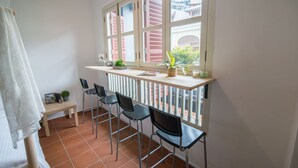 A balcony with a white railing, a wooden table, and four black chairs. There are potted plants on the table and a view of a traditional building outside. - Garden Of Eden Houses (George Town)