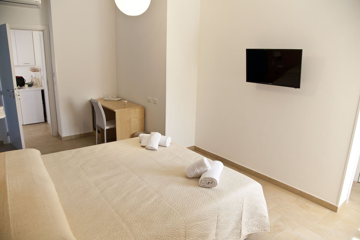 Hotellihuoneessa on sänky, työpöytä, tuoli ja seinälle asennettu televisio.