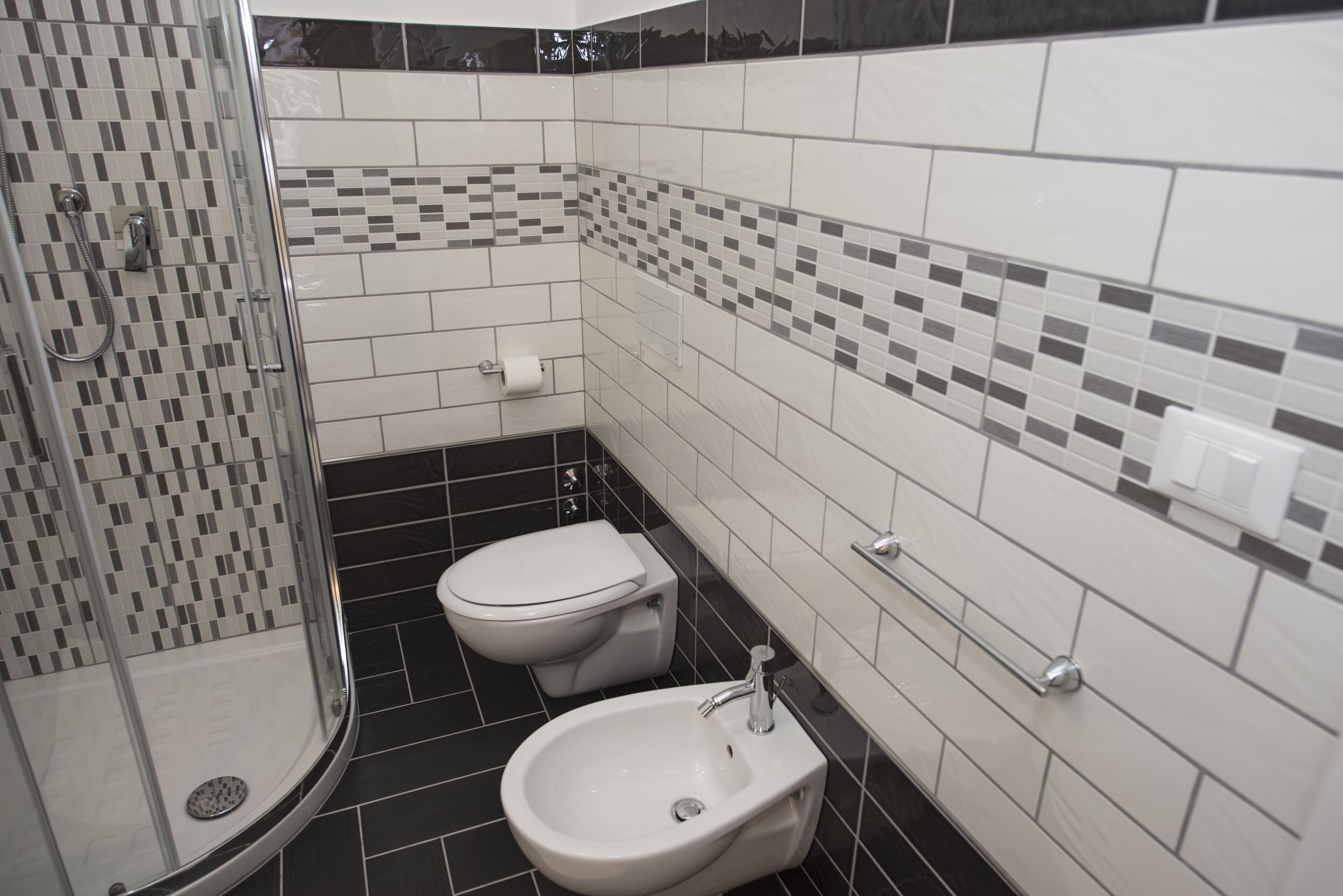 A bathroom with a shower, toilet, bidet, and tiled walls.