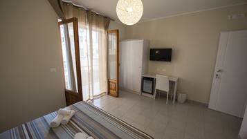 A hotel room with a bed, a desk, a television, and a wardrobe.