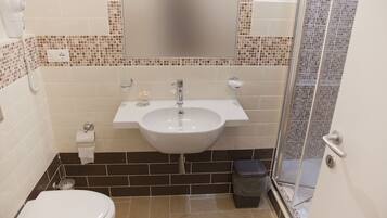 A bathroom with a white sink, a toilet, and a shower area.