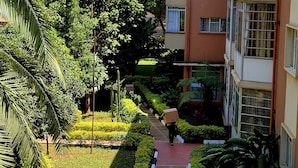 A pathway flanked by lush greenery and buildings. - United Kenya Club (Nairobi)