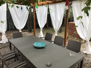 An outdoor patio with a table, chairs, and white curtains. - Mills 6, a well-equipped family home with a large garden (Guardistallo)