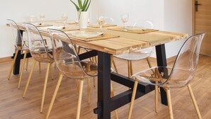 Een eettafel met transparante stoelen, een plant in pot en vier wijnglazen.