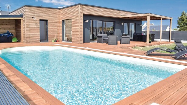 Een modern zwembadgedeelte met een houten terras, een overdekte zithoek en een helderblauw zwembad.