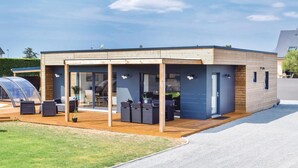 Een modern, gelijkvloers gebouw met een overdekte patio, grote ramen en een autoport.