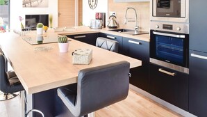 Een moderne keuken met een houten kookeiland, zwarte kastjes, een Samsung oven en een ingebouwde magnetron.