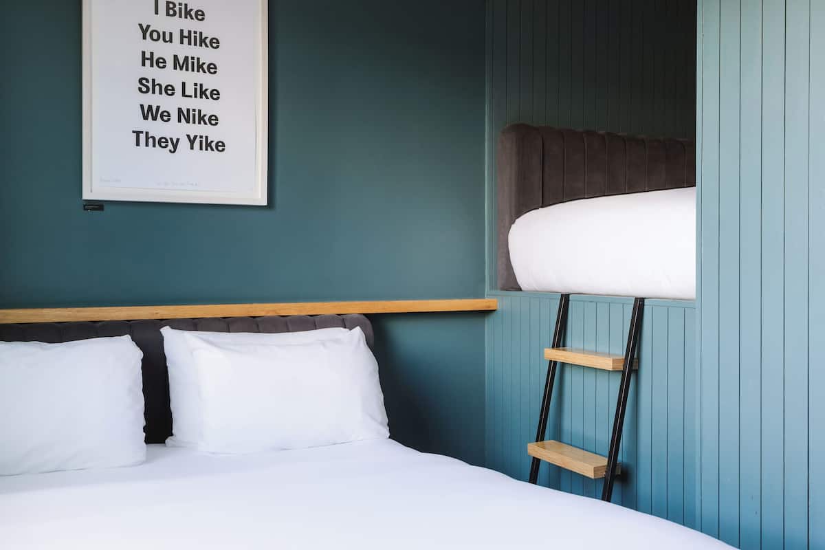 A bedroom with a bed, a headboard, a ladder, and a wall-mounted sign.