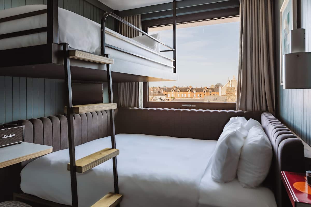 A bunk bed room with a view of buildings through a window.